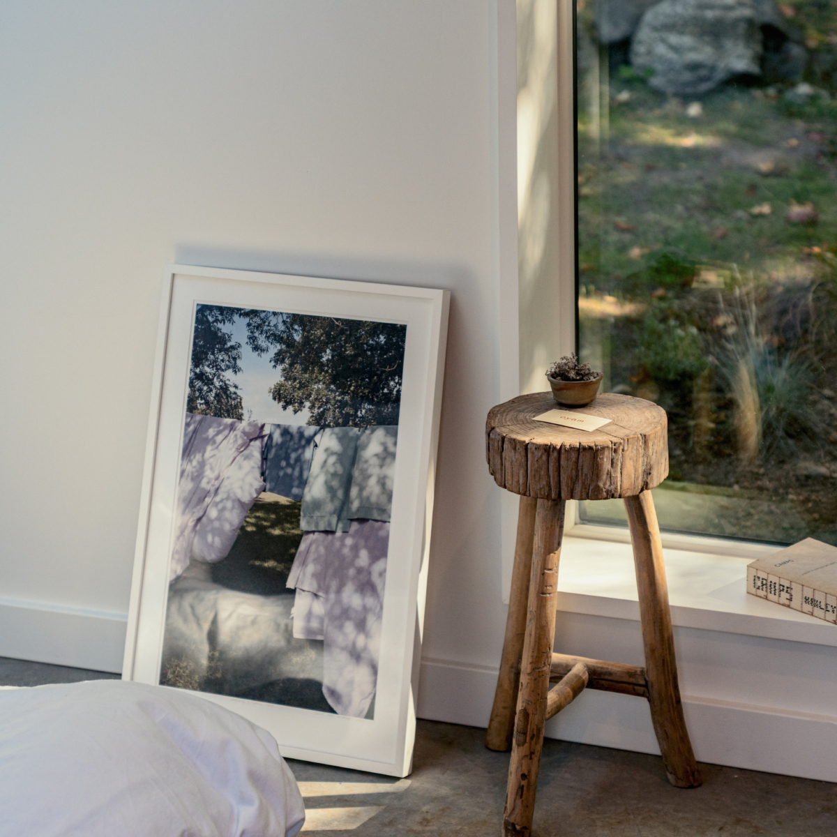 Architectural window sill with dappled light and wooden stool.