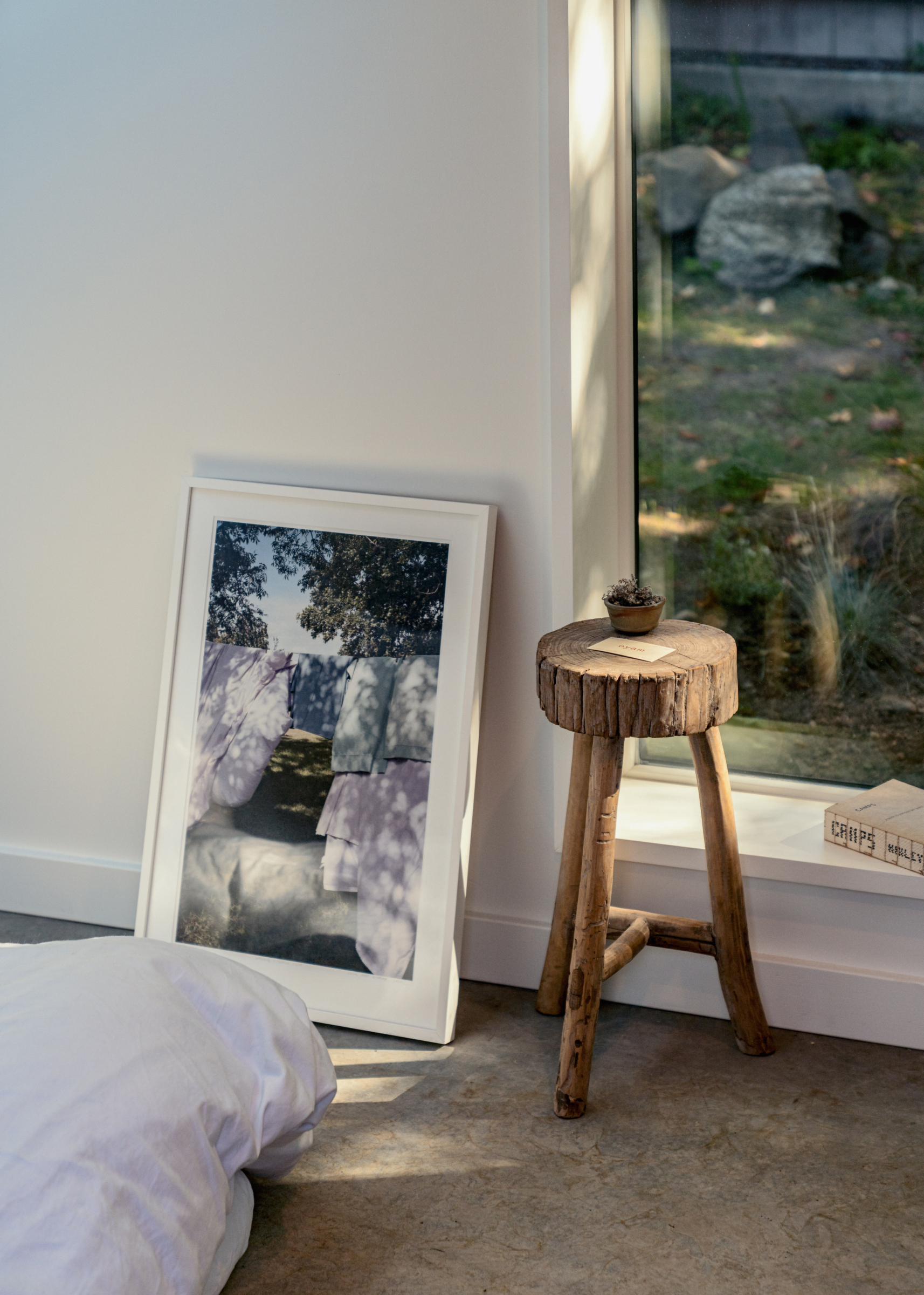 Architectural window sill with dappled light and wooden stool.